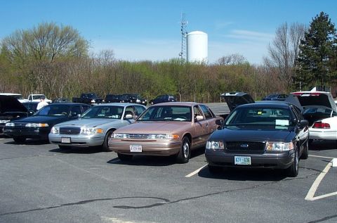 1991 Ford LTD Crown Victoria - Several Ford Crown Victoria sedans are parked in an outdoor lot under a clear blue sky.