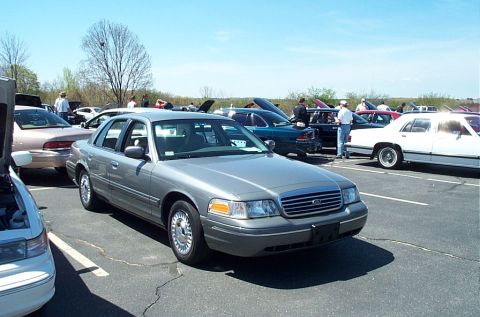 1991 Ford LTD Crown Victoria - A gray Ford Crown Victoria is parked at a car show with other vehicles visible.