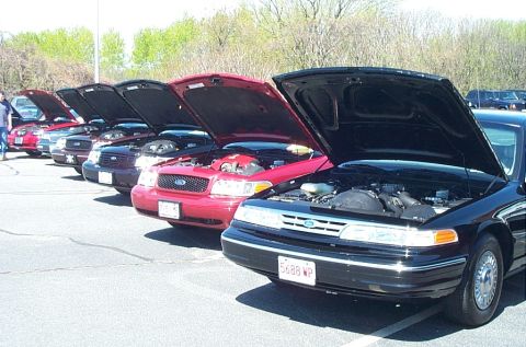 1991 Ford LTD Crown Victoria - Several Ford Crown Victorias are lined up with their hoods open, displaying their engines.