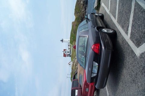 1991 Ford LTD Crown Victoria - A dark sedan is parked near a lighthouse and other vehicles.