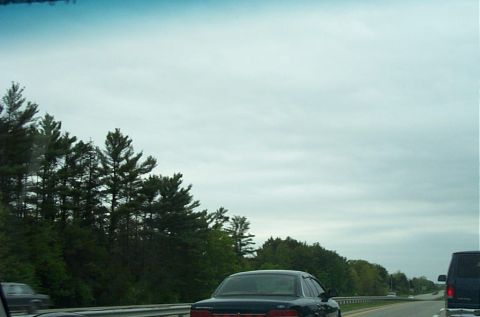 1991 Ford LTD Crown Victoria - A dark 1991 Ford Crown Victoria LTD sedan is seen from the rear on a highway under a cloudy sky.
