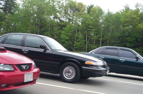 1991 Ford LTD Crown Victoria - A black Ford Crown Victoria sedan is seen driving on a road, with other vehicles nearby.