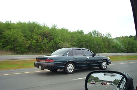 1991 Ford LTD Crown Victoria - Dark green 1991 Ford Crown Victoria LTD travels down the highway under an overcast sky.