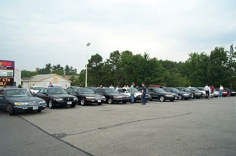 1991 Ford LTD Crown Victoria - Multiple sedans are parked in a lot under an overcast sky.