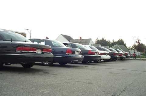 1991 Ford LTD Crown Victoria - A row of black and blue sedans, likely 1991 Ford Crown Victoria LTDs, are parked in a lot.