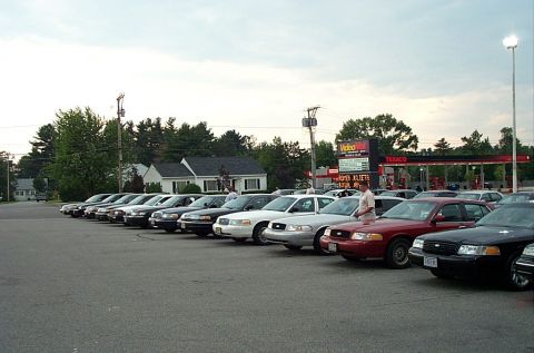 1991 Ford LTD Crown Victoria - Several Ford Crown Victoria police cars are parked in a lot near a gas station.