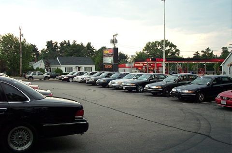 1991 Ford LTD Crown Victoria - Multiple sedans are parked in a lot with a gas station in the background.