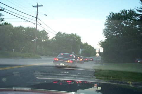1991 Ford LTD Crown Victoria - Multiple vehicles are seen on a road during the daytime, with trees lining the sides.