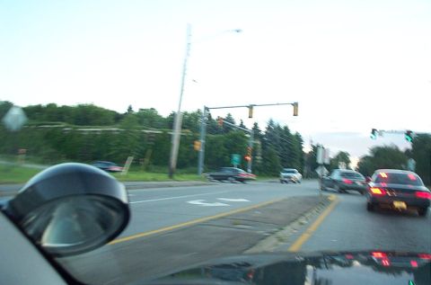 1991 Ford LTD Crown Victoria - Traffic moves along a road with multiple vehicles visible under an overcast sky.