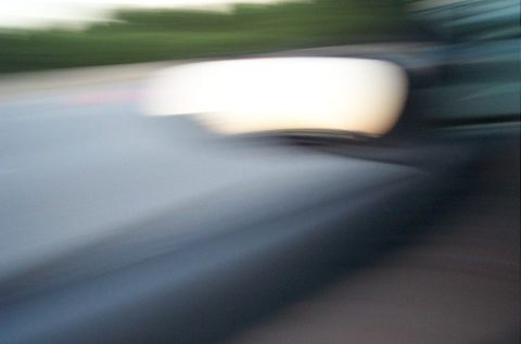 1991 Ford LTD Crown Victoria - Motion blur obscures the details of a car's side mirror and hood, making identification impossible.