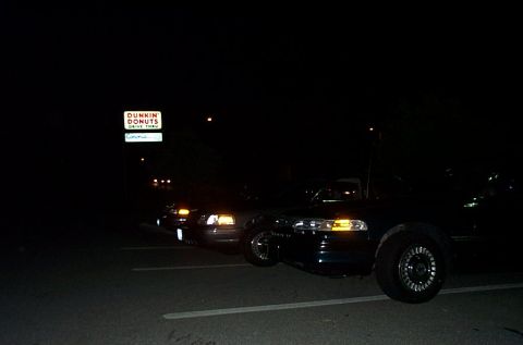 1991 Ford LTD Crown Victoria - Two Ford Crown Victorias are parked at night, with a Dunkin' Donuts sign visible in the background.