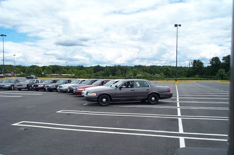 1991 Ford LTD Crown Victoria - A row of police interceptor sedans are parked in a lot under a cloudy sky.