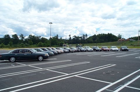 1991 Ford LTD Crown Victoria - A line of sedans are parked in a lot under a cloudy sky.