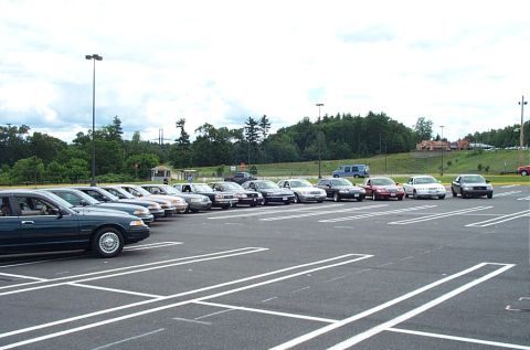 1991 Ford LTD Crown Victoria - A row of sedans, including a dark green 1991 Ford Crown Victoria LTD, are parked in a lot under a cloudy sky.