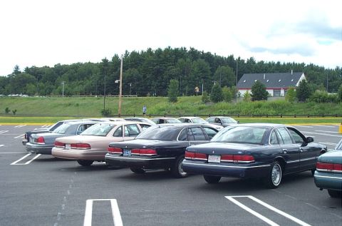 1991 Ford LTD Crown Victoria - Several Ford Crown Victoria LTD sedans are parked in a lot under a cloudy sky.