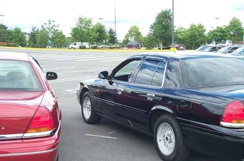 1991 Ford LTD Crown Victoria - A black 1991 Ford Crown Victoria LTD sedan is parked next to a red sedan in a parking lot.
