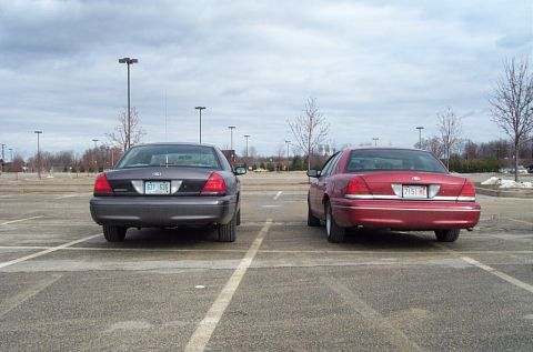 1991 Ford LTD Crown Victoria - Two Ford Crown Victorias are parked in an empty lot under a cloudy sky.