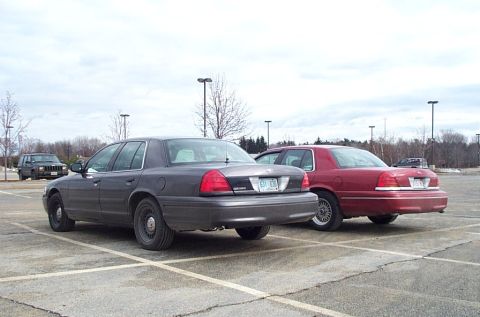 1991 Ford LTD Crown Victoria - Two Ford Crown Victorias are parked side-by-side in a parking lot under an overcast sky.