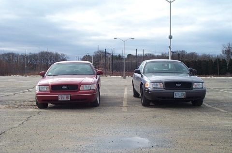 1991 Ford LTD Crown Victoria - Two Ford Crown Victorias are parked in an empty lot under a cloudy sky.