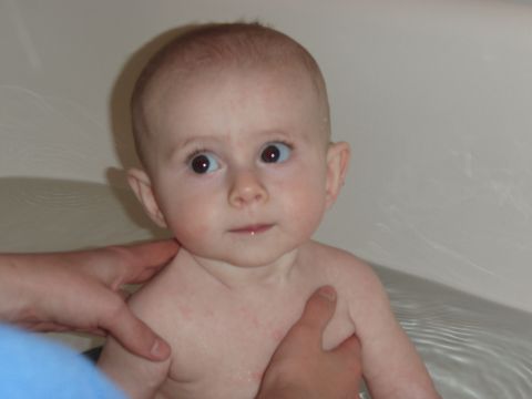1997 Ford F-250 - A baby is being bathed in a bathtub, held by two sets of hands.
