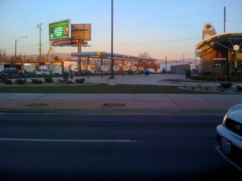 1983 Ford Bronco - A view of a gas station and a billboard at dusk, with a portion of a car visible in the foreground.