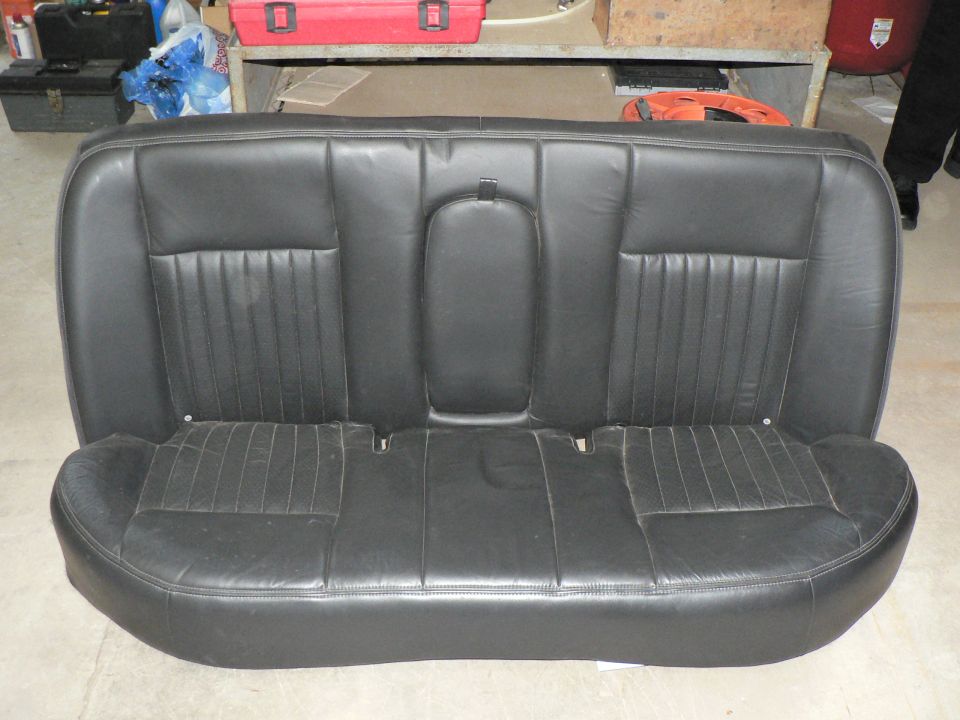 Black leather rear bench seat removed and sitting in a garage