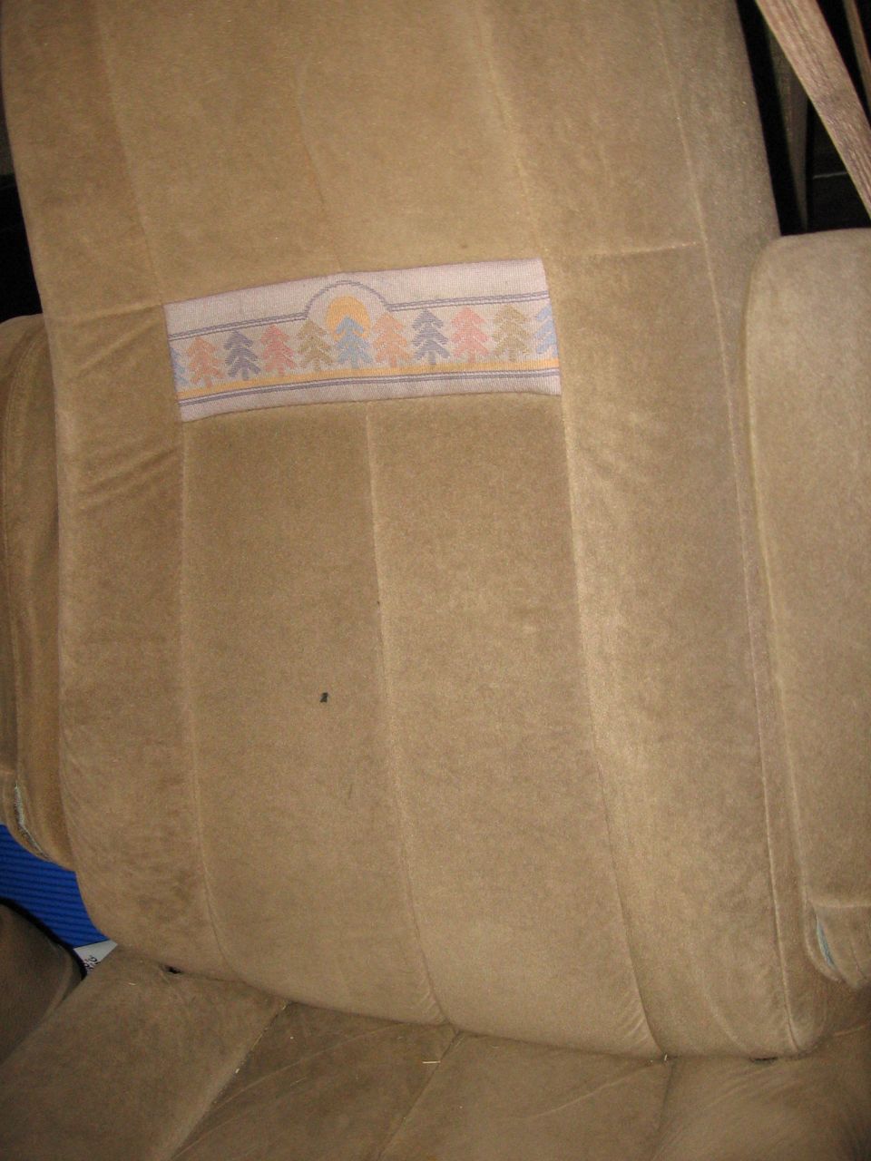 Tan fabric car seat upholstery with a decorative strip trees and a sun