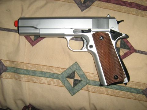 1988 Mercury Grand Marquis - A silver pistol with brown grips rests on a patterned blanket, showing a red tip.
