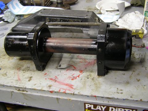 1993 Ford Bronco - A black winch part with a copper drum sits on a workbench, likely awaiting installation or repair.