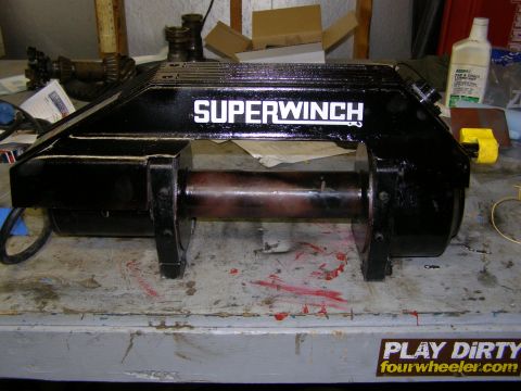 1993 Ford Bronco - A Superwinch electric winch sits on a cluttered workbench, ready for installation or repair.