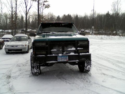 2000 Chevrolet Tahoe - A green truck with a heavy-duty aftermarket bumper and aggressive tires sits in a snowy lot.