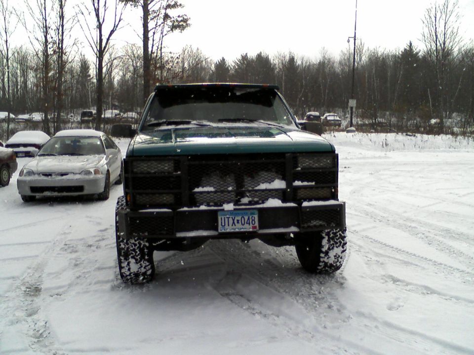 Green truck front view with aftermarket bumper and snow-covered tires