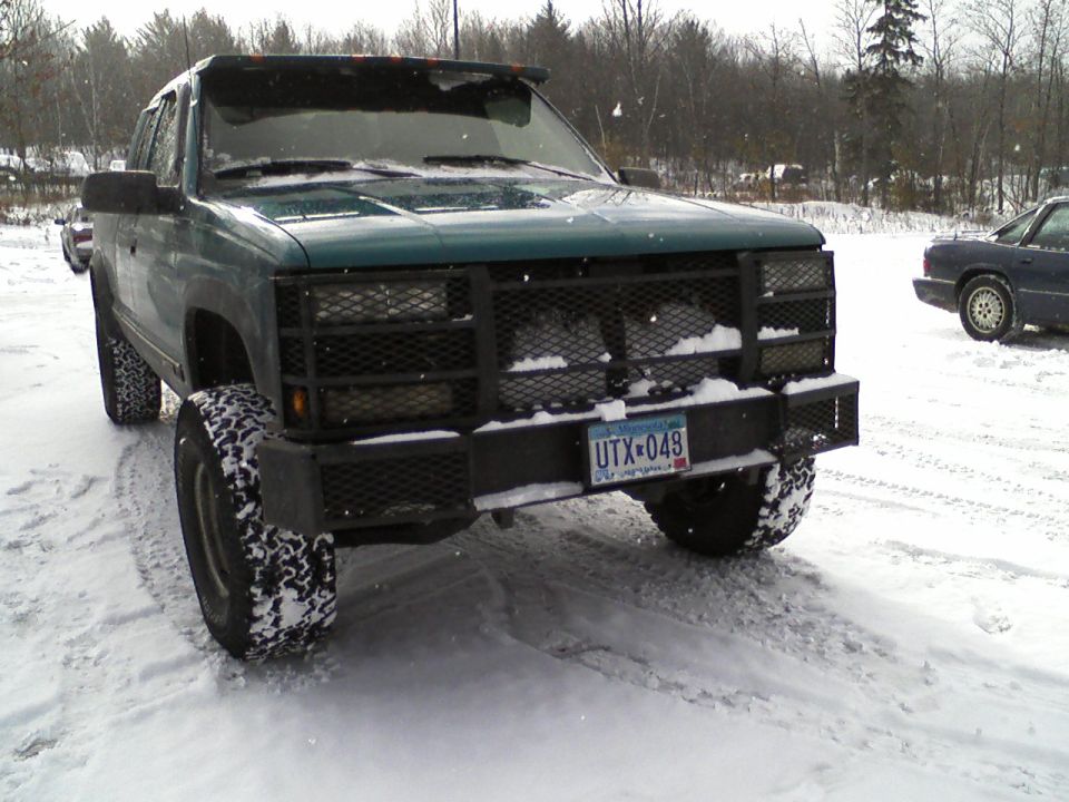 Green pickup truck with aftermarket bumper and grille guard in snow. License plate UTX-049