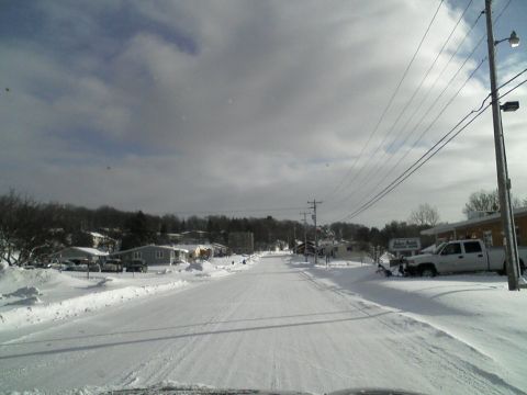 2000 Chevrolet Tahoe - A snow-covered street in a residential area with a white pickup truck equipped with a snowplow.