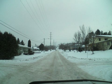 2000 Chevrolet Tahoe - A snow-covered road winds through a residential area under an overcast sky.