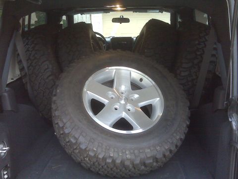 2008 Jeep Wrangler - Spare tires are loaded into the cargo area of a 2007 Jeep Wrangler, with a silver rim prominently displayed.