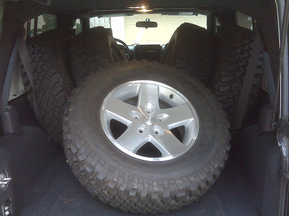 Interior of a 2007 Jeep Wrangler with spare tires and a silver rim in the foreground