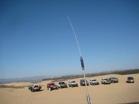 1989 Ford Bronco - A group of off-road vehicles are parked in the sand dunes on a clear day.