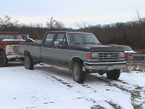 1987 Ford Bronco - 1987 Ford Bronco F-Series pickup truck in a snowy outdoor setting with another truck nearby.