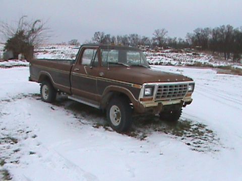 1987 Ford Bronco - A brown Ford F-Series pickup truck sits in a snowy field under an overcast sky.