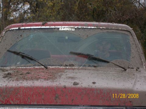1988 Ford Bronco - This red SUV is heavily covered in mud, obscuring most of its details.