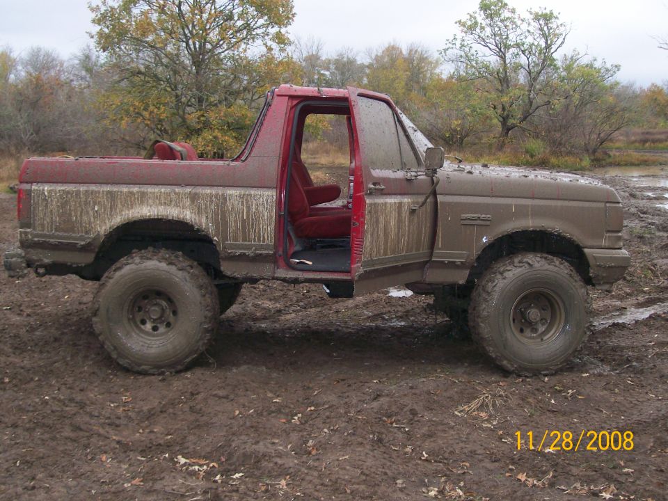 Mud-covered 1987-1991 Ford Bronco with doors open, stuck in mud