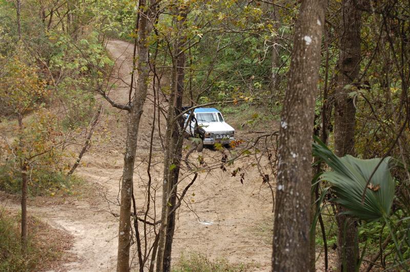 White pickup truck with blue trim on a dirt road, seen from above