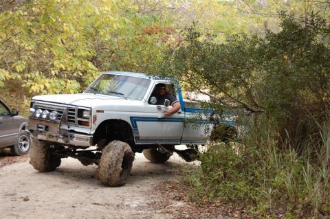 1982 Ford F-100 - Off-road adventure in a 1982 Ford F-100, navigating a wooded trail with a companion vehicle nearby.