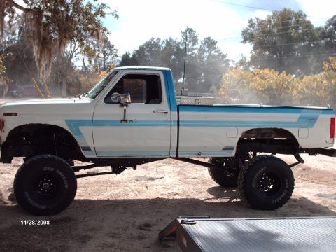 1982 Ford F-100 - This lifted pickup truck has a distinctive side stripe and a toolbox mounted in the bed.