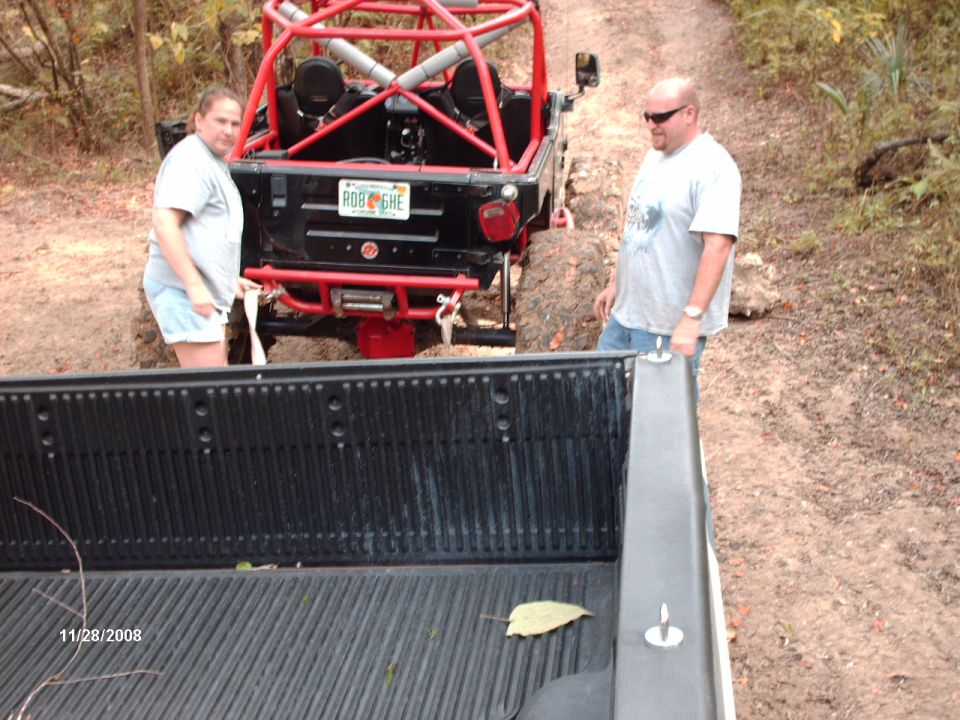Black off-road vehicle with red roll cage and bumper, seen from the rear