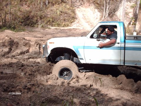 1982 Ford F-100 - This 1982 Ford F-100 is stuck deep in the mud, with the driver looking out the window.