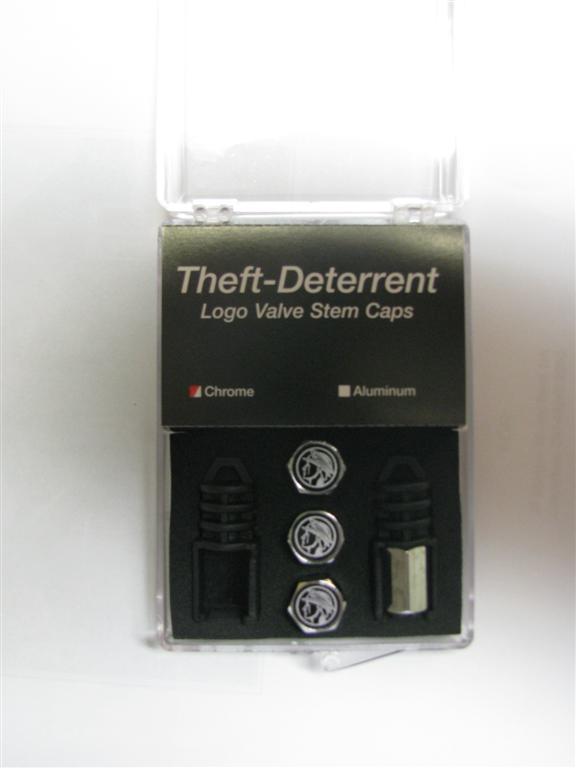 Box of theft-deterrent logo valve stem caps. Includes two black caps, three silver caps with a logo, and one silver hexagonal cap