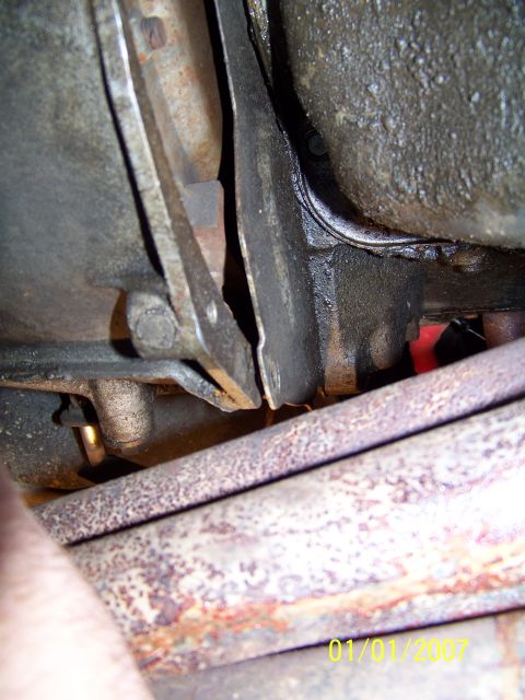 1985 Ford Bronco - Close-up of vehicle undercarriage parts, showing rust and grease, with a watermark.