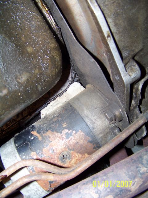 1985 Ford Bronco - Close-up view of a vehicle's starter motor, showing signs of rust and wear.